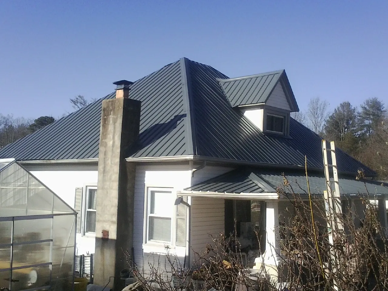 Dark blue standing seam metal roof on a white farmhouse with dormer — Slate & Tile Roof Repair by Roofing Brothers in Denville