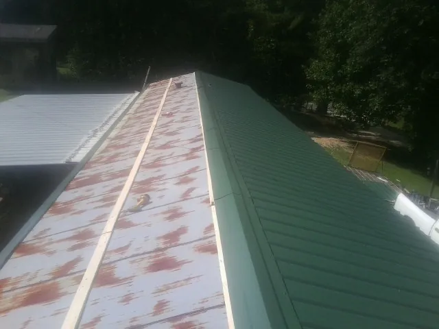 Old rusted panels beside newly installed green metal roofing — Wind Damage Roof Repair by Roofing Brothers in Denville