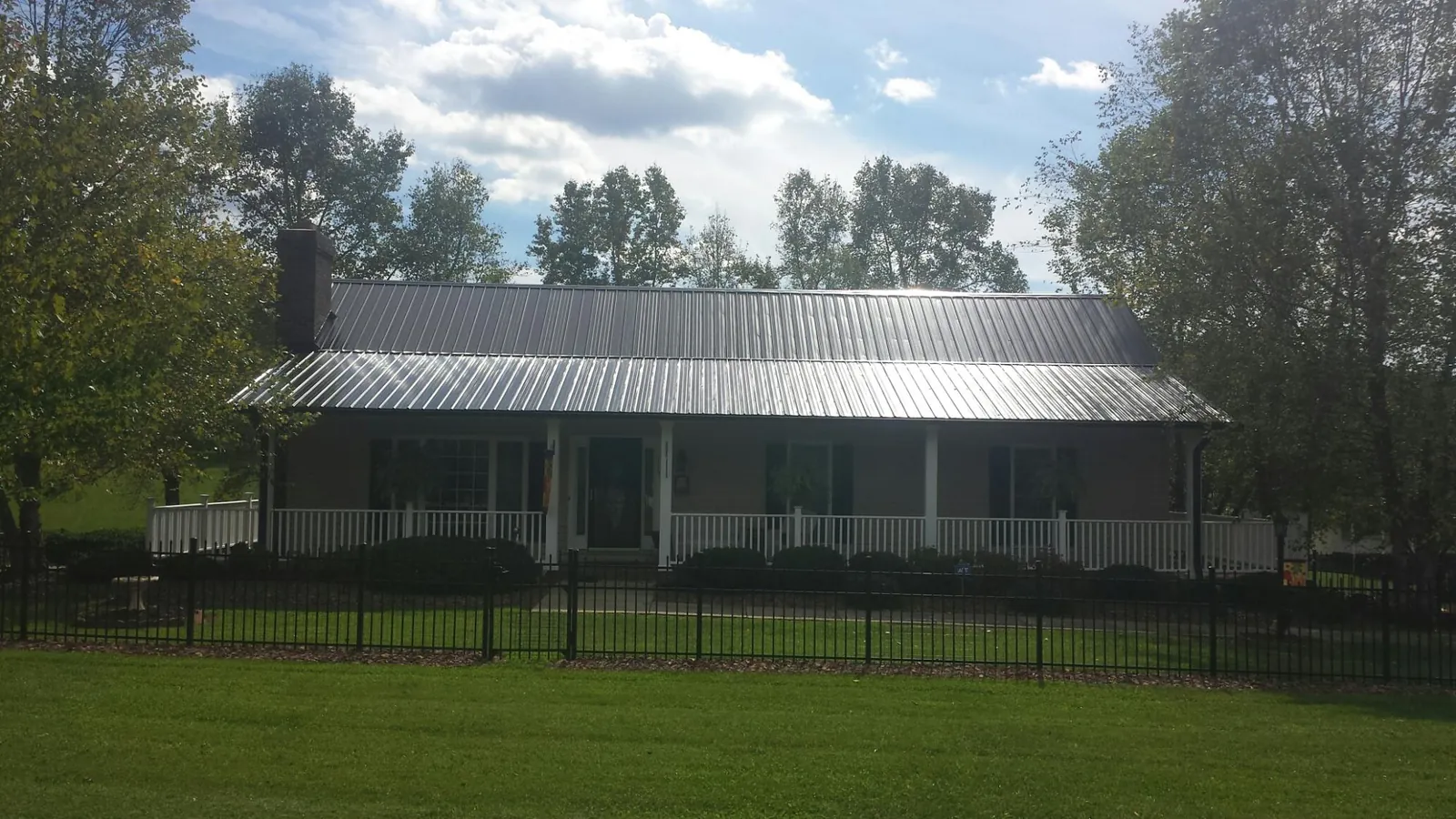 Gray metal roof on a brick ranch with a full width front porch — Gutter Guard Installation work by our crew in Denville