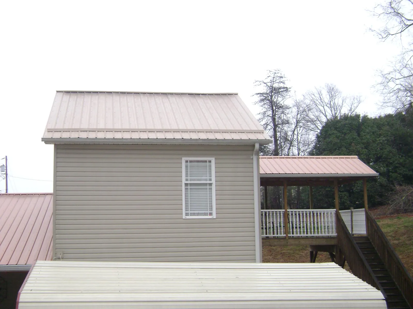 Tan metal roofs on a two story addition and attached porch, from a Roof Replacement job in Denville