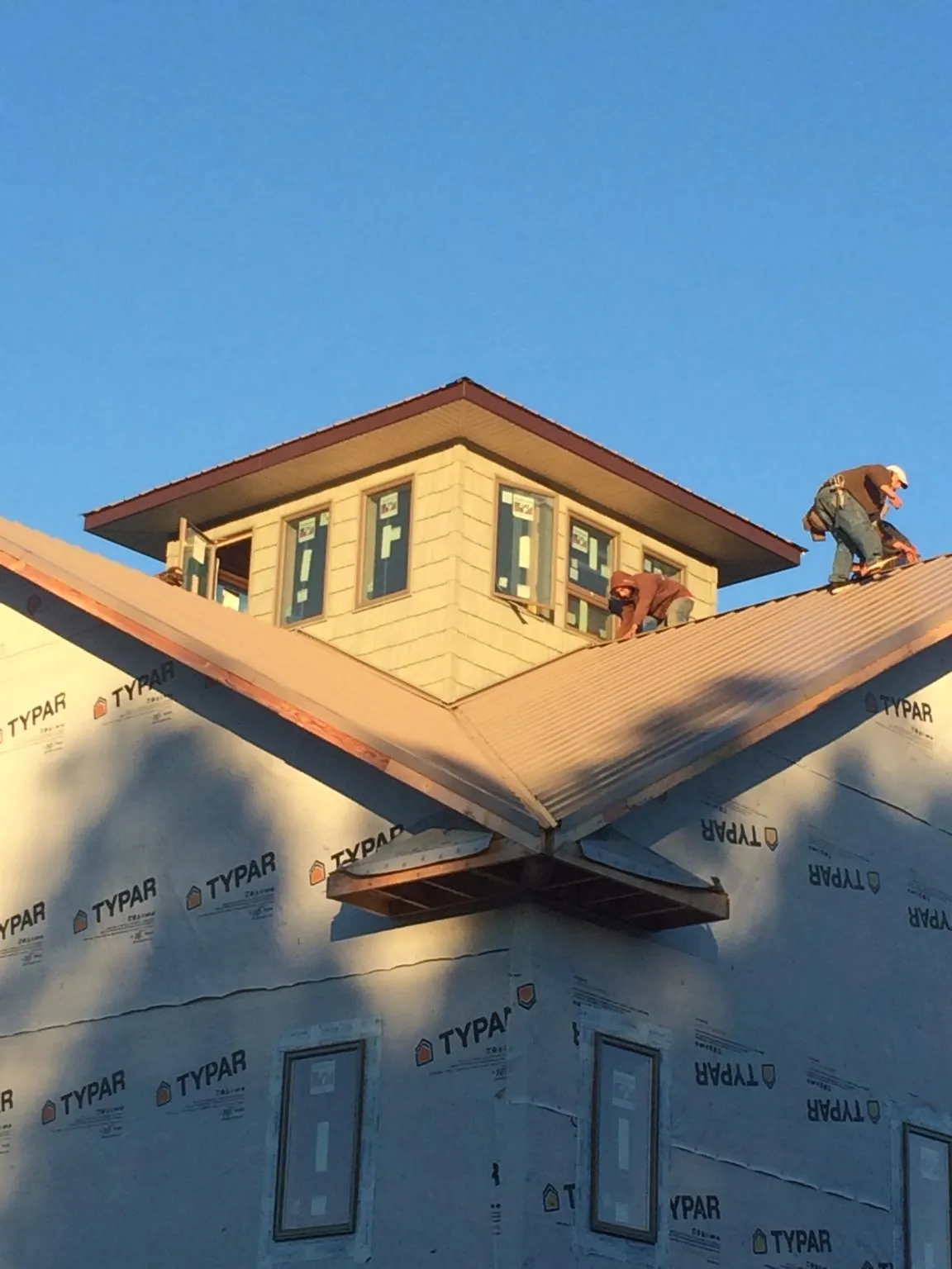 Roofers working around a rooftop cupola on a new metal roof at sunset — Roof Waterproofing in Denville by Roofing Brothers